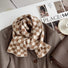 Close-up of a plaid scarf in beige and khaki draped over a brown blazer, great for office layering and commuting.