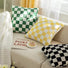 Front view of Three soft cotton checkerboard pillow covers in green, yellow, and black on couch.