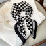 Close-up of the black and white square scarf tied elegantly around a white garment.