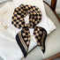 The caramel and black checkerboard scarf tied into a bow.