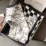 Front view of Satin square scarf with abstract black and white patterns and a checkered border, great for office.