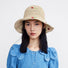 Model wearing the beige cherry straw hat for a summer beach vacation look.