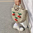 Model carrying a beige Cherry Rattan Straw Bag handheld, ideal for city walks and gifting.