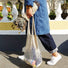 Model carrying a beige net shopper bag in hand, easy for commuting and weekends.