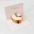 Front view of White paper pop-up birthday card with a 3D colorful cake and two candles.