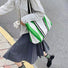Model carrying the green and white striped canvas tote bag on the street.