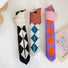 Three argyle knitted bags rolled up to show compact storage and stretchable material.