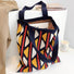 Angled view of Geometric contrast color knitted tote bag in yellow, red and blue.