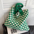 Green and white checkerboard knit tote placed on a magazine, highlighting its trendy aesthetic.