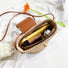 Angled view of Open mini raffia straw bucket crossbody bag with phone and cosmetics inside