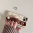 Cream quilted leather case featuring a large pearl accent and brown wrist strap.