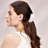 Model wearing a Shell hair claw in white luster, ideal for everyday outfits and office looks.