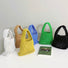 Front view of Six small multi-colored crochet cotton rope handbags in white, brown, yellow, blue, green, and black.