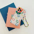Clear smiley face case featuring a Keep Smiling charm and a rainbow beaded wrist strap.