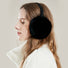 Side view of model wearing black plush earmuffs; sleek minimalist winter ear protection.