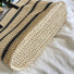 Close-up of Woven straw tote bag with black stripes, showcasing the bottom.