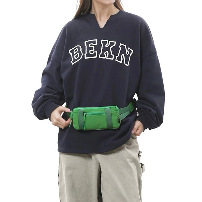 Model wearing the green airy stride mini belt bag at the waist over a sweatshirt.