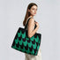 Model carrying a green arrow print tote bag on shoulder, showcasing the bold geometric style and large capacity.