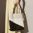 Model carrying white and black knitted artistic tote bag showcasing artisanal style for creative professional commutes.