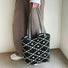Model holding the black and white geometric bucket bag by the striped handle.