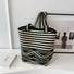 Artistic bucket bag featuring a complex mix of horizontal stripes and geometric patterns.