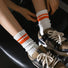 Model wearing a pair of orange striped cotton socks, ideal for everyday outfits and sneakers.