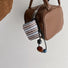 Close-up of Beaded Melody Wrap Airpods Case Cover hanging on a handbag, ideal for gifting and everyday use.