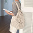 Model wearing beige foldable backpack featuring ultralight polyester and secure drawstring storage.