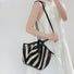 Model carrying the black and white striped basket bag on her should with the long strap style, ideal for city walks and gifting.