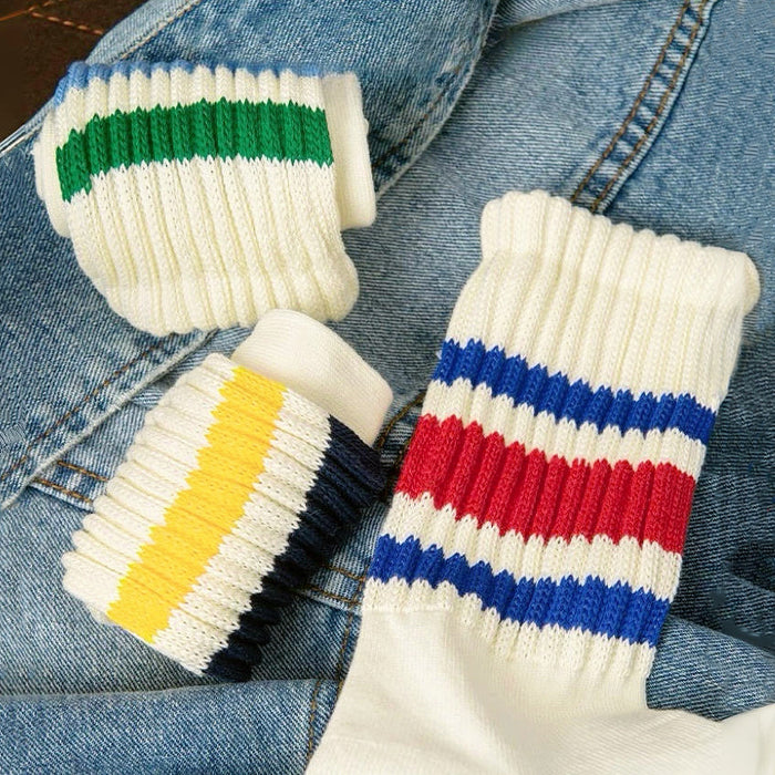 White Blockcore Slouch Socks with colorful stripes (red/blue, yellow/navy, green/blue) on ribbed cotton-polyester fabric.