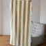 Model holding up a fully unfolded Bold Color Striped Bath Towel in white-mustard, great for bath time.
