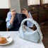 Front view of light blue Braided Handle Denim Handbag putting on a table, easy for commuting and weekends.