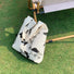 White canvas tote bag with black butterfly embroidery on green grass.
