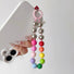 Model holding a phone with  white phone case and rainbow Candy Bead Phone Charm .