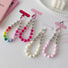 Four acrylic candy bead phone charms in rainbow, pink, rose red and crean white.