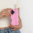 Model holding the vibrant pink and white striped wavy case against a white top.