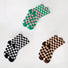 Flat lay of 3 pairs of Checkerboard Colored Socks, green, black and brown.