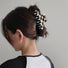Model wearing checkerboard hair claw in cross shape, ideal for quick updos and ponytails.