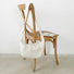 The off-white ruched crescent bag displayed on a wooden chair.