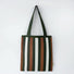 Close-up of Polyester knitted tote bag with vertical stripes in dark green, brown, and white.