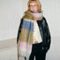 Model wearing Wool blend Cloudy Pastel Scarf with soft, muted pink, blue, green, and white stripes in beige.
