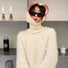 Person wearing white textured sweater and a soft-knit hood with vibrant red trim balaclava hat.