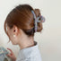 Model wearing a Colored Yarn Hair Claw  in gray, ideal for quick updos and ponytails.