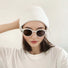 Woman wearing white knitted beanie with sunglasses, a chic accessory for urban winter street style.