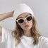 Model styling a clean white acrylic ribbed beanie hat paired with casual white t-shirt.