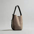 Detailed view of the grey convertible suede bag with its structured bucket shape.