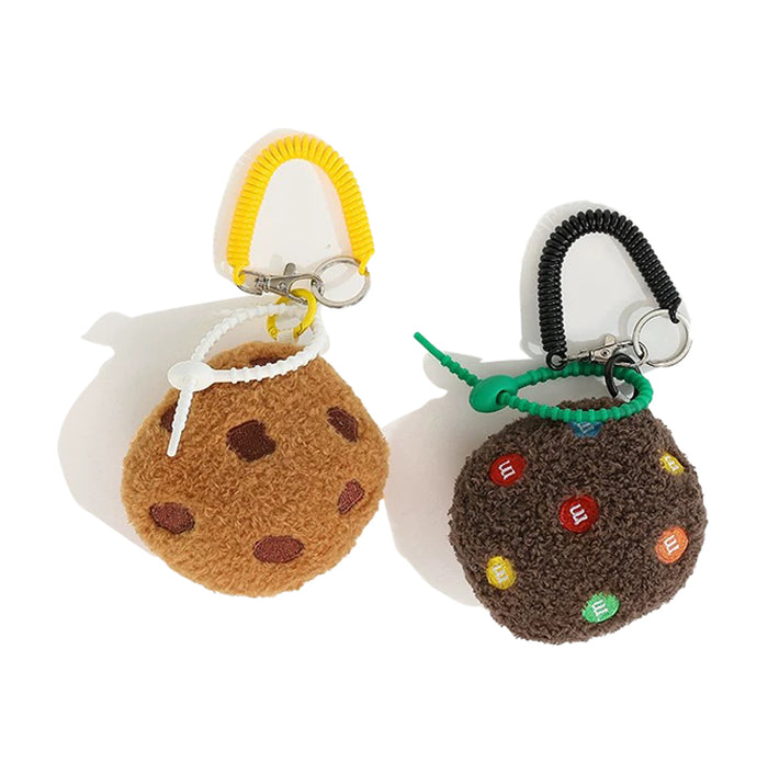 Two fluffy polyester cookie bag charms: one light brown with chocolate chips and a yellow spiral clip, the other dark brown with colorful candy pieces and a black spiral clip.