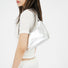 Silver patent leather shoulder bag with a sleek, minimalist design, worn by a woman.