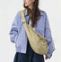 Model wearing a large khaki corduroy crescent bag over a checkered jacket.