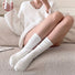 White cotton slouch socks on legs, paired with a cozy white sweater.